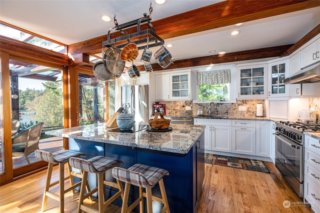 kitchen featuring a center island, stainless steel appliances, white cabinetry, and light hardwood / wood-style floors