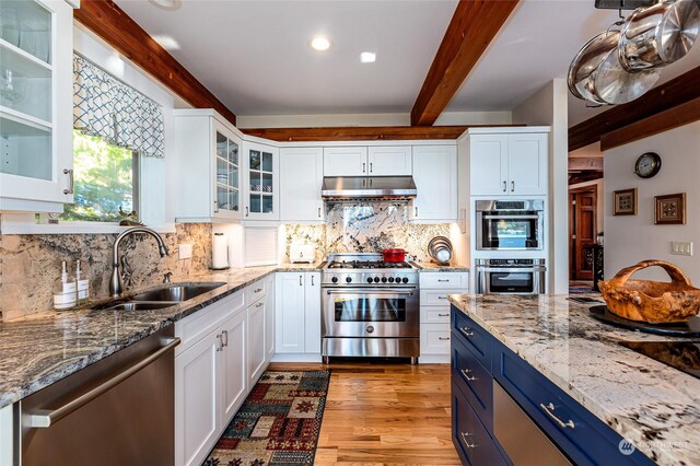 308 De Haro Ln, San Juan Island, WA 98250 - kitchen featuring beamed ceiling, under cabinet range hood, a sink, appliances with stainless steel finishes, and blue cabinetry