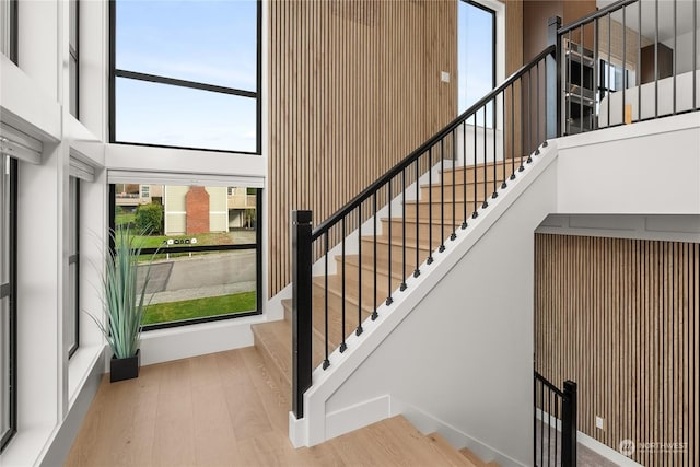 entrance foyer featuring wooden walls, light hardwood / wood-style flooring, and a towering ceiling