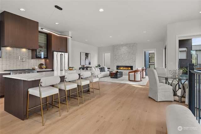 kitchen featuring a breakfast bar, light wood-type flooring, high quality fridge, dark brown cabinets, and a kitchen island