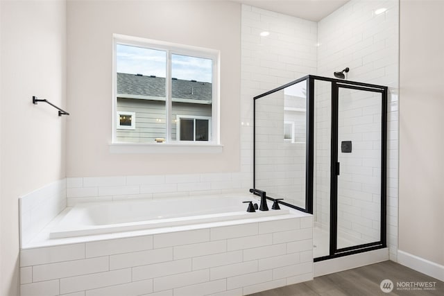 bathroom featuring a stall shower, wood finished floors, and a bath