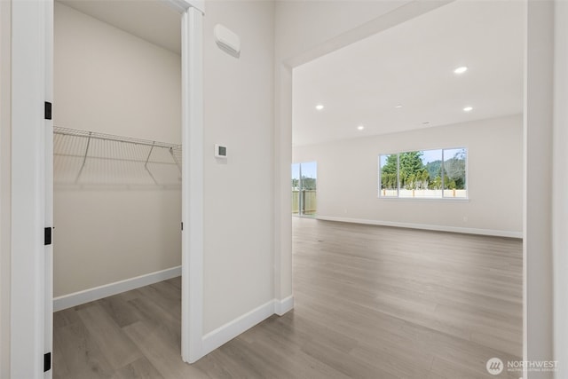 corridor featuring baseboards, wood finished floors, and recessed lighting