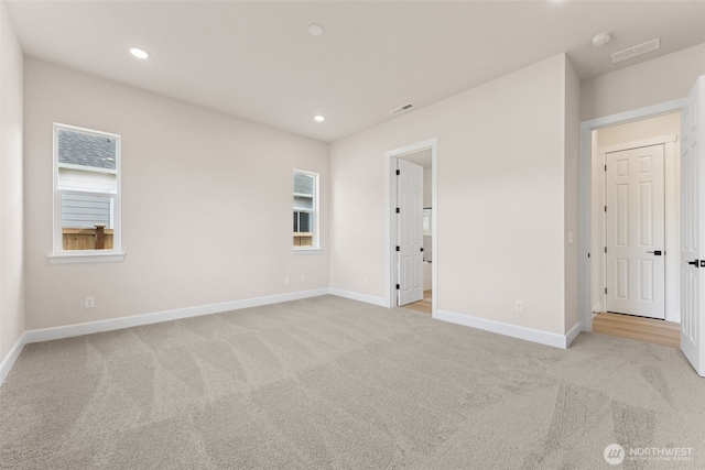 carpeted empty room with baseboards, visible vents, and recessed lighting