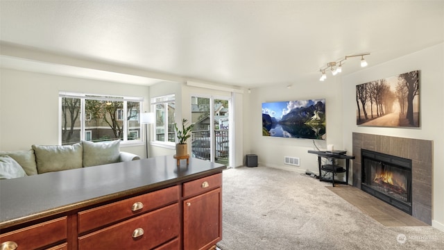 carpeted living room featuring a tiled fireplace