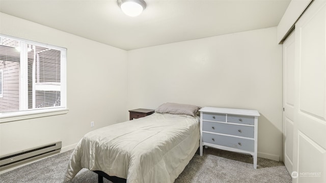 carpeted bedroom with a closet and a baseboard heating unit