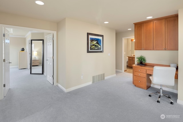 office with light colored carpet, ornamental molding, and built in desk