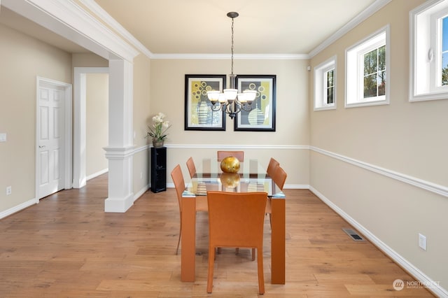 dining room featuring a notable chandelier, crown molding, ornate columns, and wood-type flooring