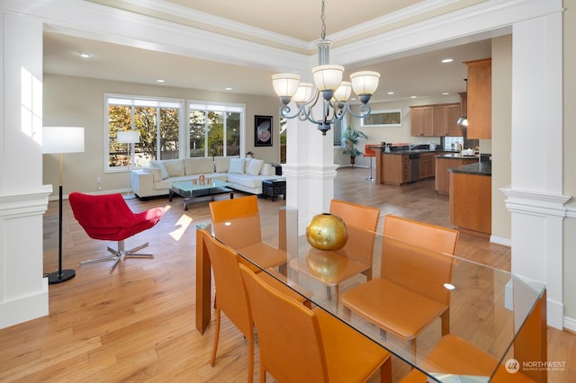 dining space with decorative columns, light hardwood / wood-style floors, ornamental molding, and a chandelier