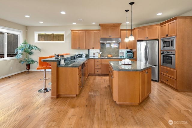 kitchen with appliances with stainless steel finishes, a center island, and light wood-type flooring