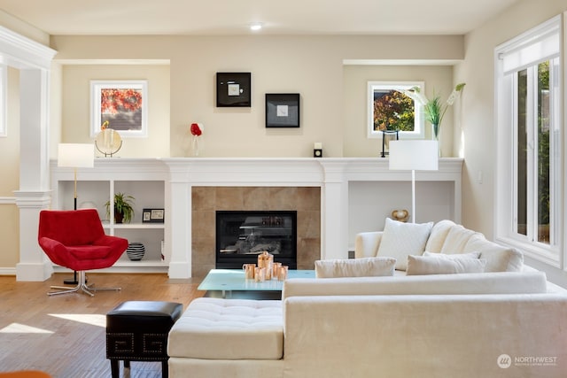 living room with a healthy amount of sunlight, wood-type flooring, and a tile fireplace