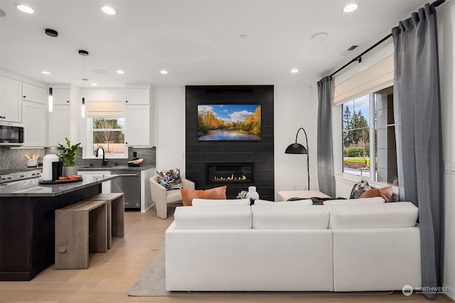 living room with a large fireplace, light hardwood / wood-style flooring, and sink