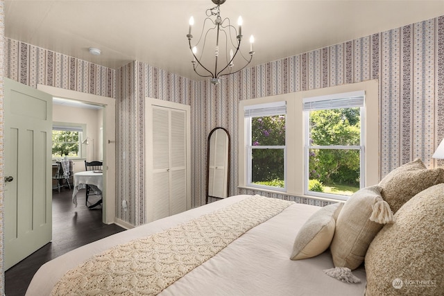 bedroom featuring an inviting chandelier, dark wood-type flooring, and a closet