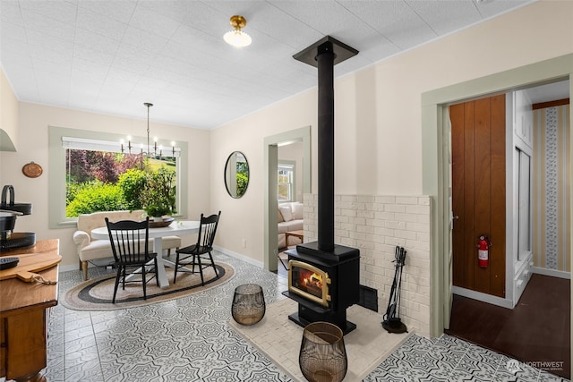 dining area with a notable chandelier, a healthy amount of sunlight, a wood stove, and light wood-type flooring