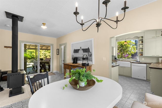 dining area featuring an inviting chandelier, a wood stove, and sink