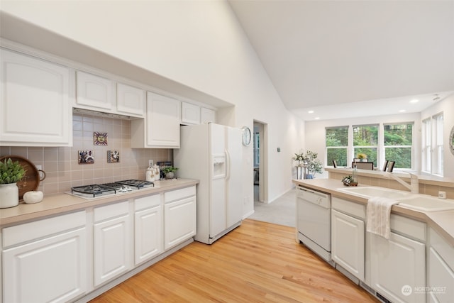 kitchen featuring light hardwood / wood-style floors, white cabinets, tasteful backsplash, and white appliances