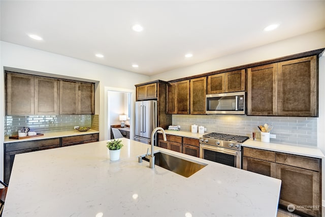 kitchen with sink, light stone counters, backsplash, and premium appliances