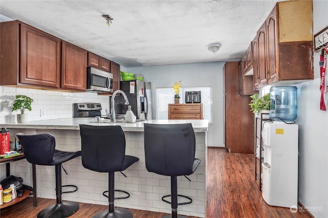 kitchen with appliances with stainless steel finishes, a breakfast bar area, and dark hardwood / wood-style flooring