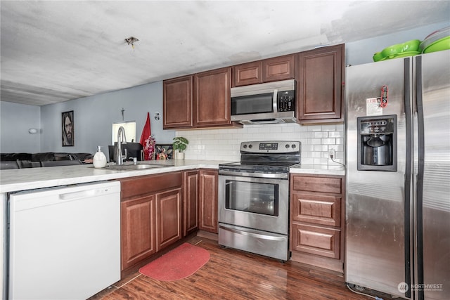 kitchen featuring sink, kitchen peninsula, stainless steel appliances, and dark hardwood / wood-style floors