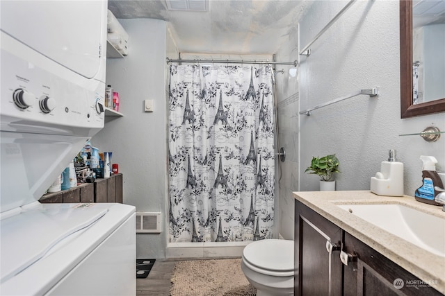 bathroom with hardwood / wood-style floors, toilet, stacked washer / drying machine, vanity, and curtained shower