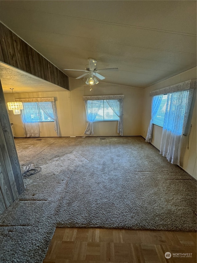 unfurnished room featuring ceiling fan with notable chandelier, plenty of natural light, and vaulted ceiling