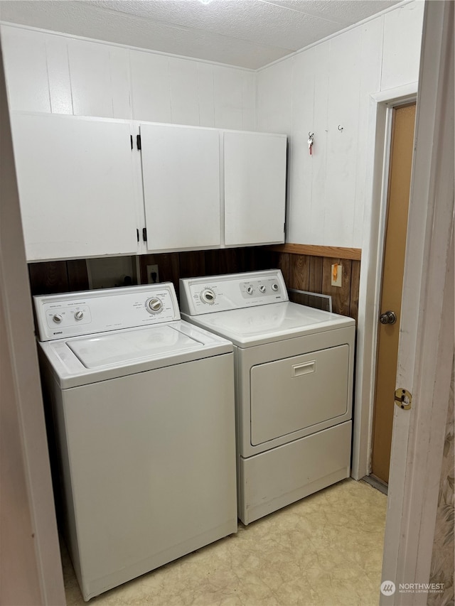 washroom featuring washer and dryer, a textured ceiling, and cabinets