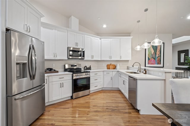 kitchen with stainless steel appliances, light hardwood / wood-style floors, kitchen peninsula, sink, and decorative light fixtures