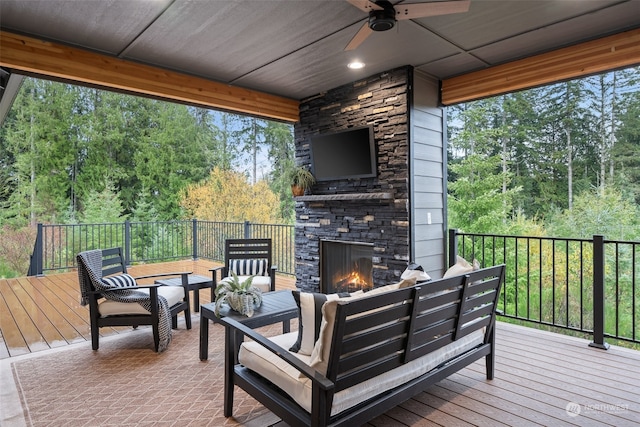 wooden terrace featuring ceiling fan and an outdoor living space with a fireplace