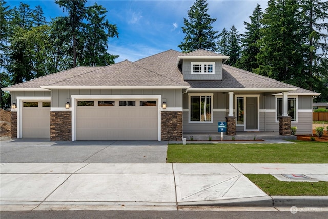 view of front of house with covered porch, a front lawn, and a garage