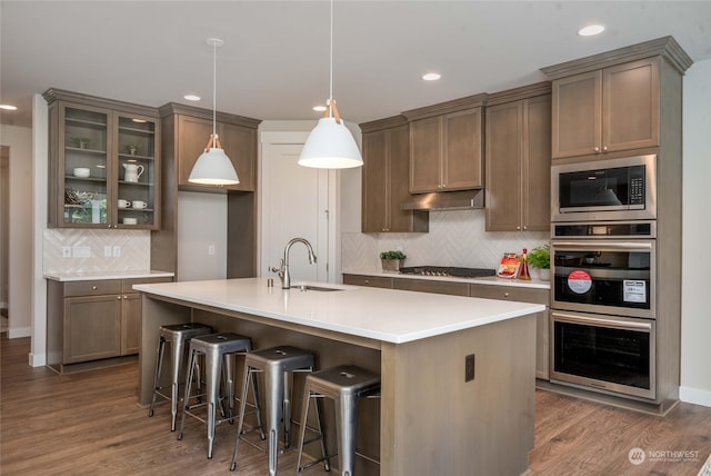 kitchen with hardwood / wood-style floors, sink, stainless steel appliances, and backsplash