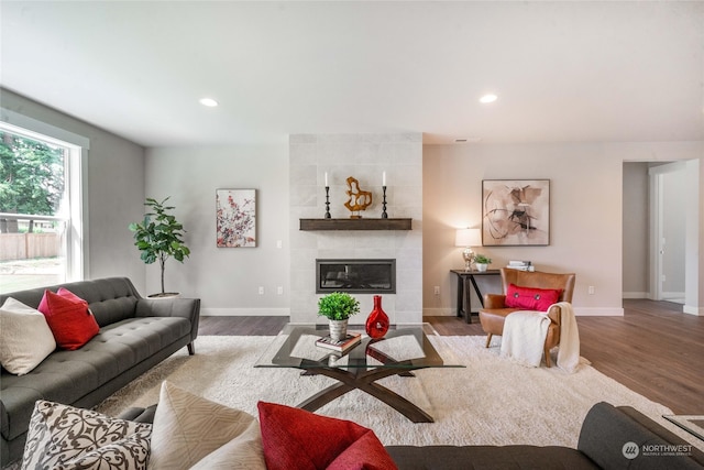 living room featuring a tiled fireplace and wood-type flooring