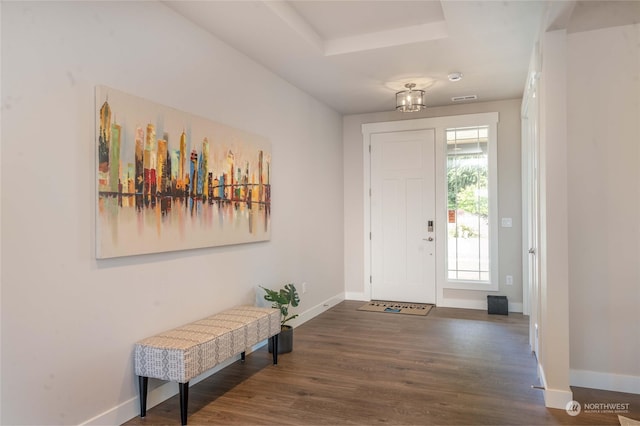 entrance foyer featuring dark wood-type flooring, a tray ceiling, and a chandelier