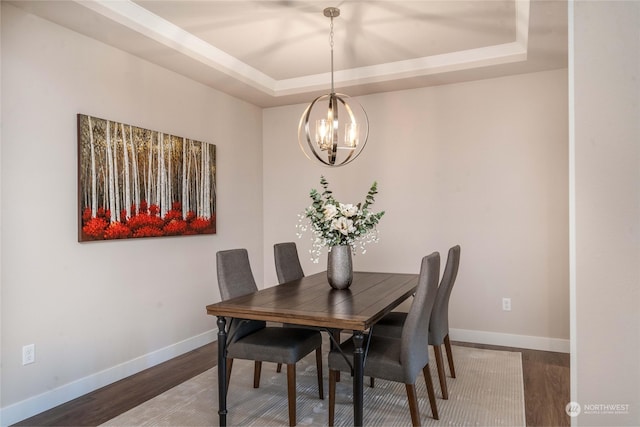 dining space featuring a notable chandelier, hardwood / wood-style flooring, and a raised ceiling