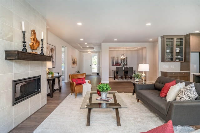 living room featuring a tiled fireplace, tile walls, dark hardwood / wood-style flooring, and an inviting chandelier