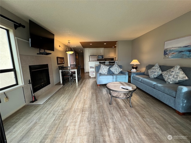 living room with a tile fireplace, a textured ceiling, and wood-type flooring