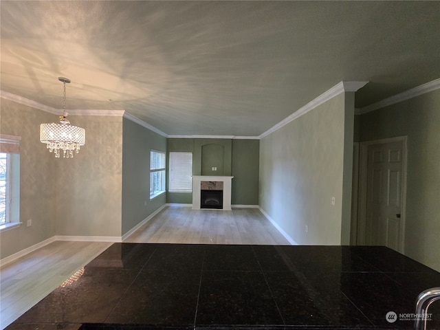 unfurnished living room with a chandelier, light hardwood / wood-style flooring, and ornamental molding