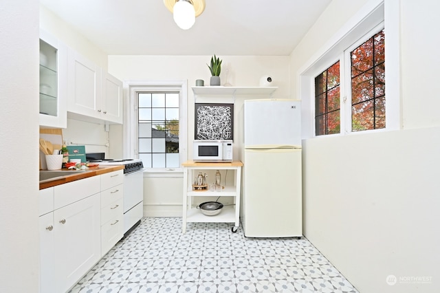 kitchen with white appliances, white cabinetry, and plenty of natural light