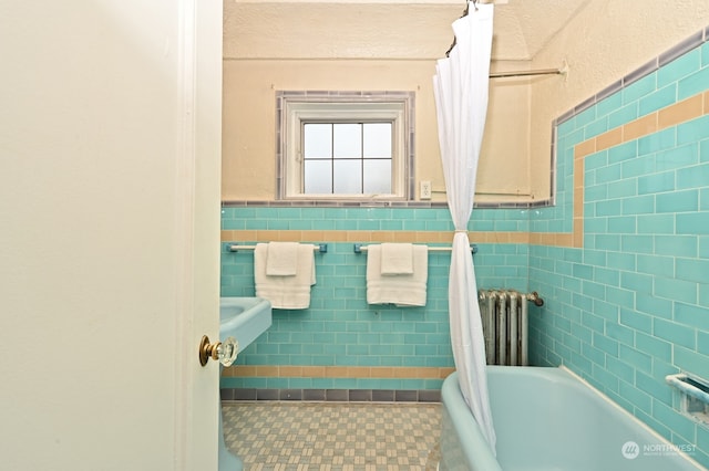 bathroom featuring tile walls, radiator heating unit, and a bath