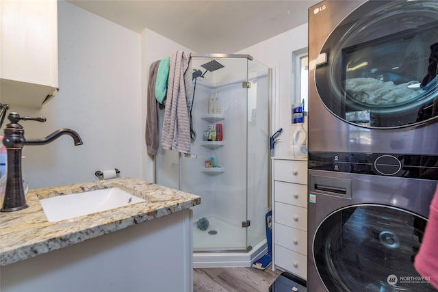 washroom with light hardwood / wood-style floors, stacked washer / drying machine, and sink