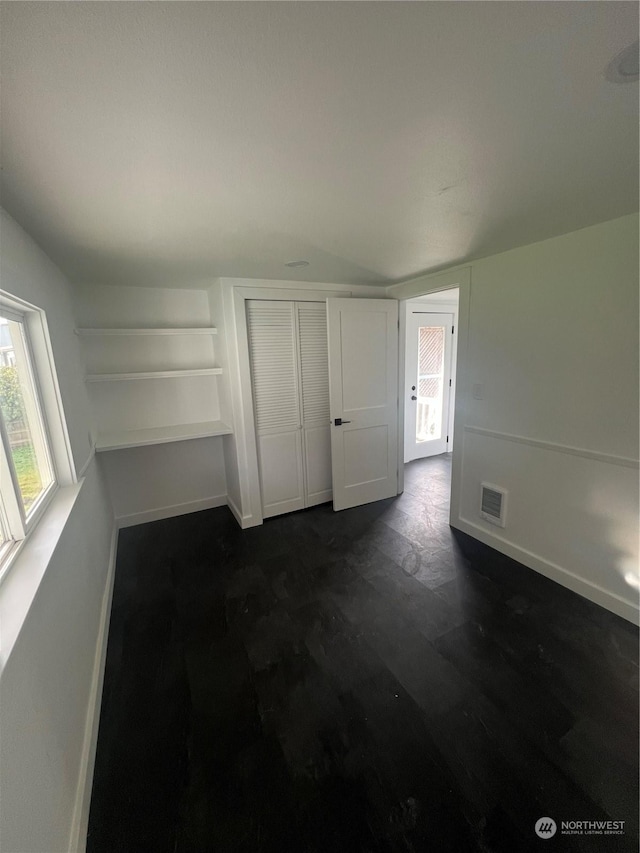 unfurnished bedroom featuring multiple windows and lofted ceiling