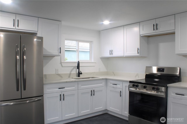 kitchen with light stone counters, white cabinetry, stainless steel appliances, and a sink