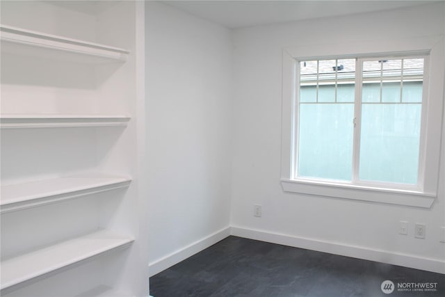 spare room with dark wood-style flooring and baseboards