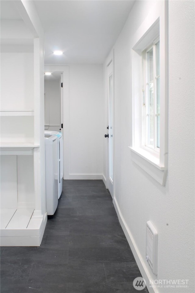 washroom with laundry area, dark wood-style flooring, washing machine and dryer, and baseboards