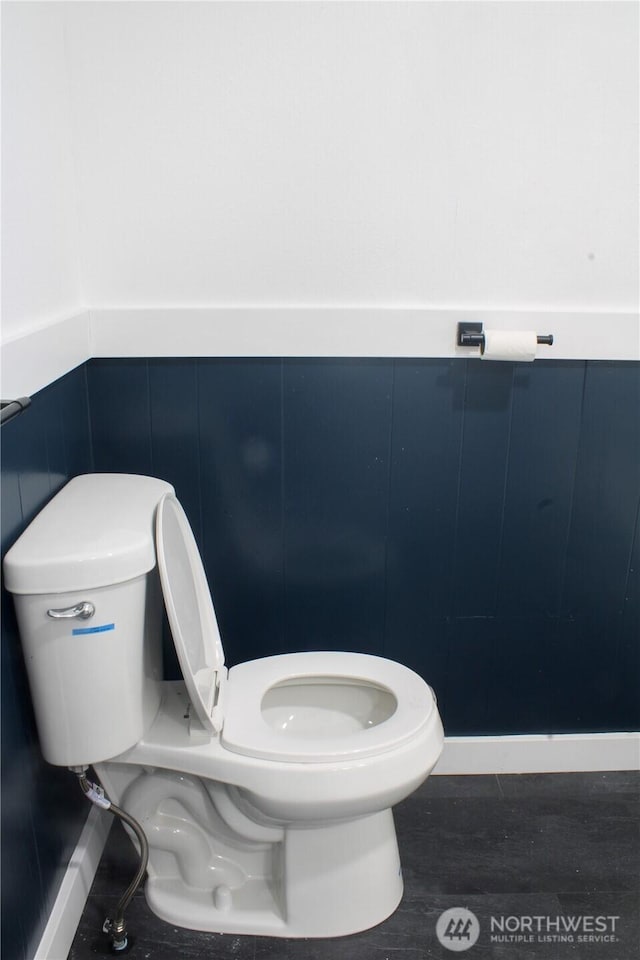 bathroom featuring a wainscoted wall, toilet, and wood finished floors