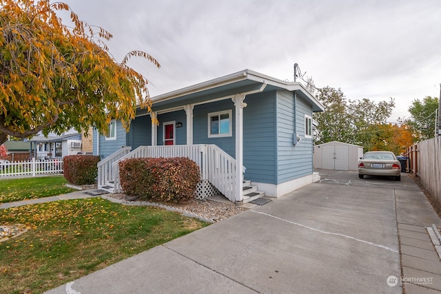 view of front of property featuring a storage shed, a front yard, and covered porch