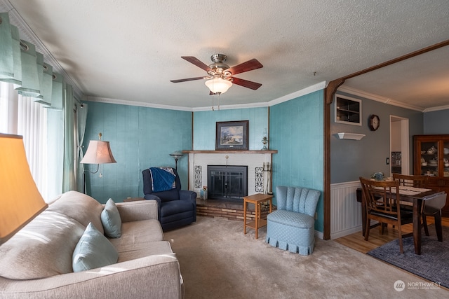 living room featuring ornamental molding, ceiling fan, a textured ceiling, a fireplace, and hardwood / wood-style floors