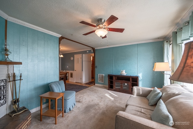 carpeted living room featuring ornamental molding, a textured ceiling, ceiling fan, and a fireplace