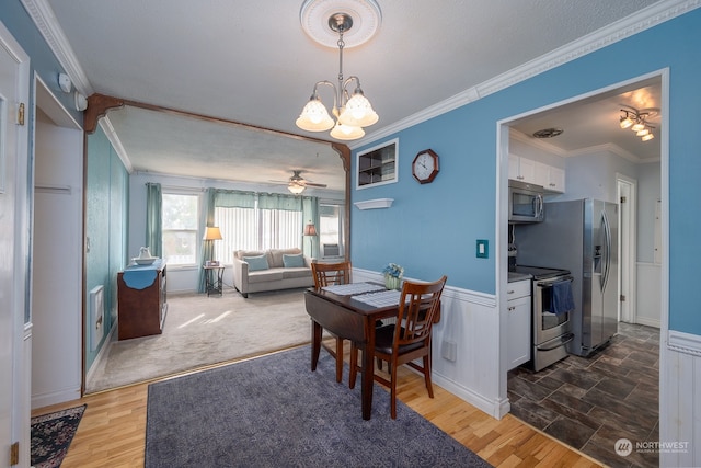 dining room with a textured ceiling, hardwood / wood-style floors, ornamental molding, and ceiling fan with notable chandelier