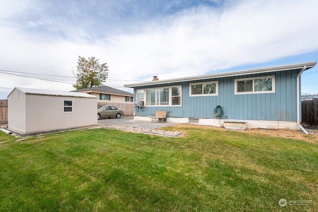 rear view of house featuring a patio, a yard, and a shed