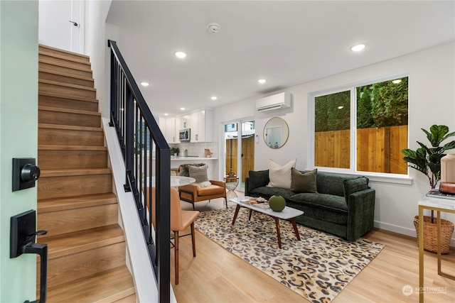 living room with light wood-type flooring and a wall unit AC