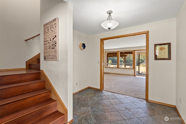 carpeted foyer with a textured ceiling